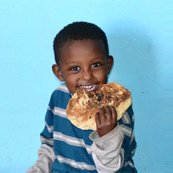 Happy child taking a bite out of Berta Pancake