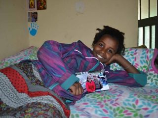 happy-child-on-bunkbed-holding-photo-of-sponsor-couple.jpg